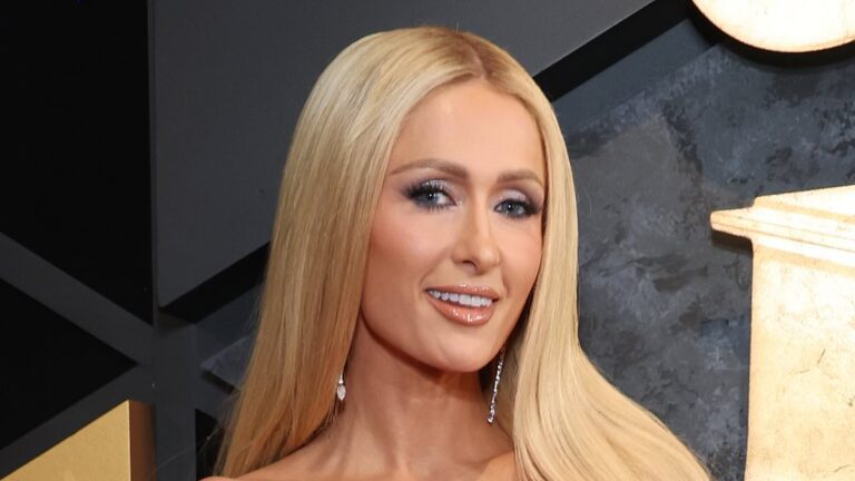 Paris Hilton dazzles in a glowing turquoise robe with dapper husband Carter Reum as they lovingly pose on the pink carpet